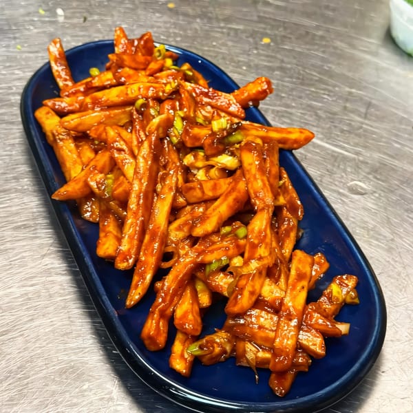 Chili Paneer, an Indian appetizer, on a blue platter with a metal background.